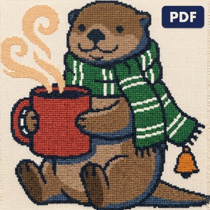A finished an otter with a mug of cocoa cross stitch piece, stitched and framed on a wall