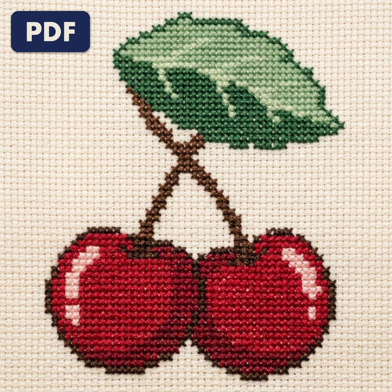 A finished cherries cross stitch piece, stitched and framed on a wall