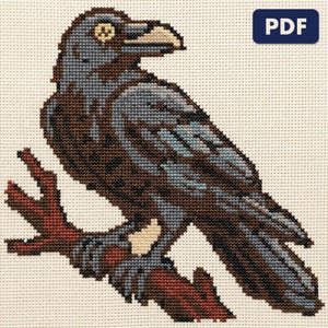 A finished raven on a bare branch cross stitch piece, stitched and framed on a wall