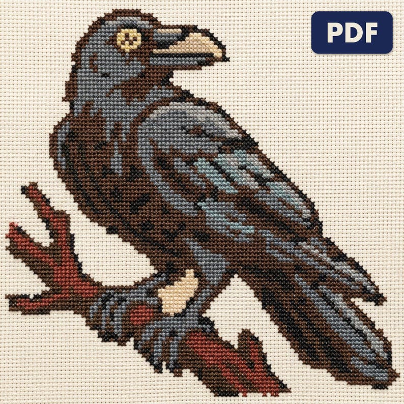 A finished raven on a bare branch cross stitch piece, stitched and framed on a wall