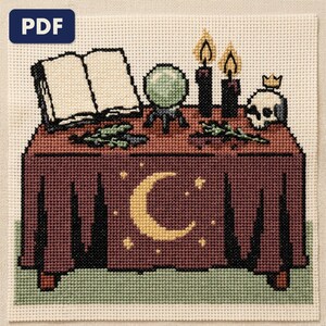 A finished an occult altar cross stitch piece, stitched and framed on a wall