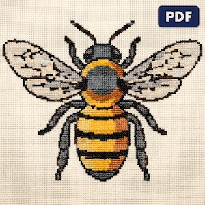 A finished a honeybee cross stitch piece, stitched and framed on a wall