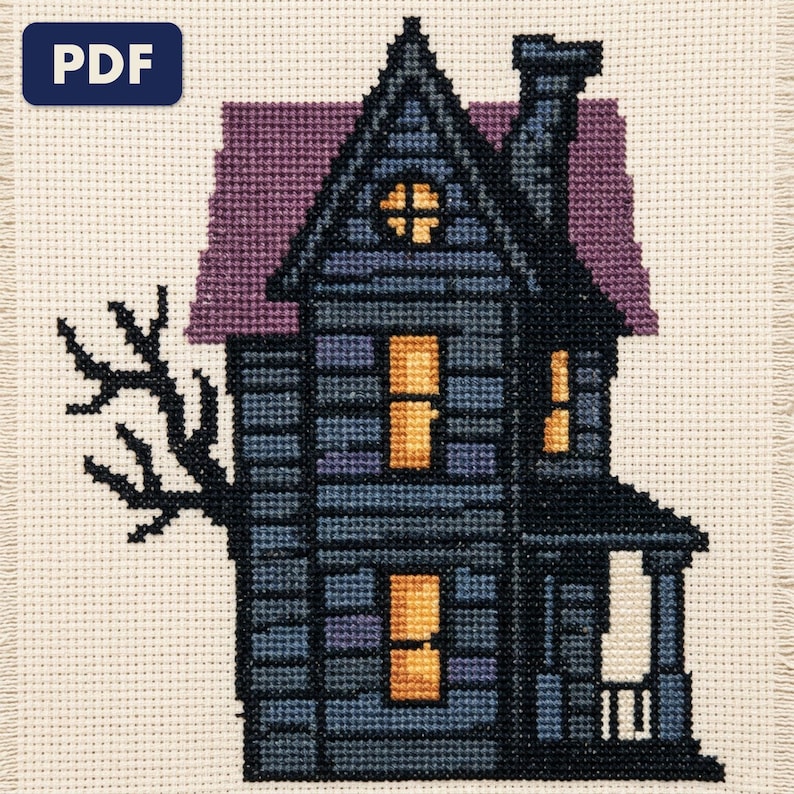 A finished haunted house cross stitch piece, stitched and framed on a wall