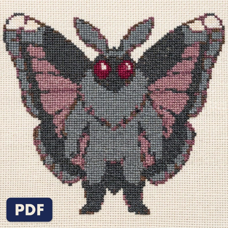 A finished mothman cross stitch piece, stitched and framed on a wall