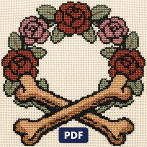 A finished rose wreath with crossed bones cross stitch piece, stitched and framed on a wall