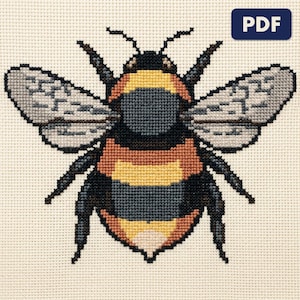 A finished a bumblebee cross stitch piece, stitched and framed on a wall