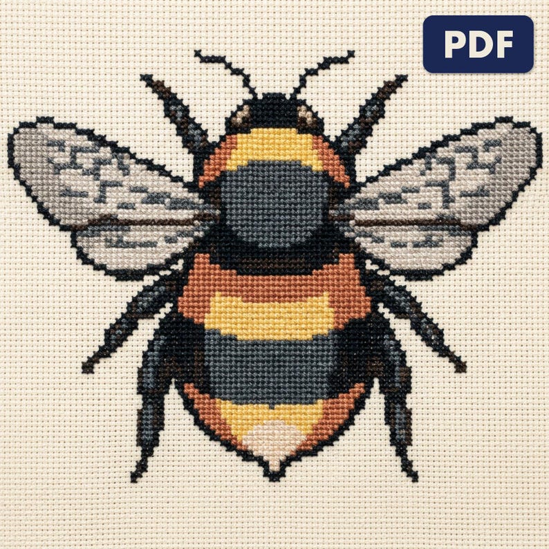 A finished a bumblebee cross stitch piece, stitched and framed on a wall