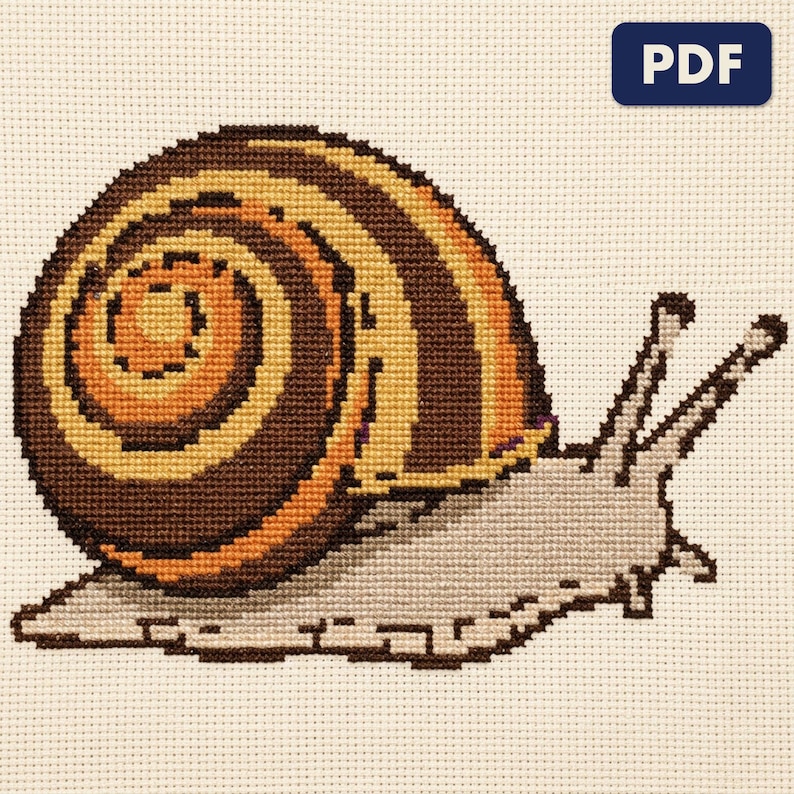 A finished a garden snail cross stitch piece, stitched and framed on a wall