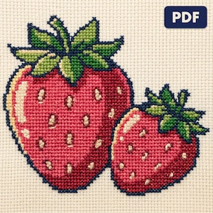 A finished strawberries cross stitch piece, stitched and framed on a wall