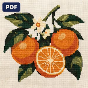 A finished an orange branch cross stitch piece, stitched and framed on a wall