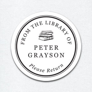 May include: Black and white round sticker with the text "From the Library of Peter Grayson Please Return" and a stack of books in the centre.
