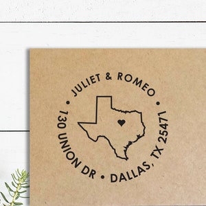 May include: A brown paper card with a black circular stamp. The stamp features the outline of Texas with a heart, surrounded by the text "JULIET & ROMEO" and address details: "130 UNION DR • DALLAS, TX 25471".