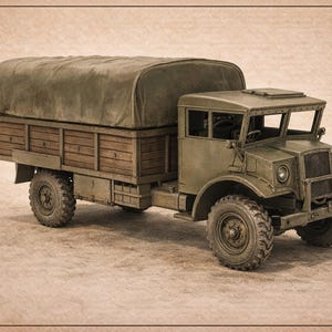 May include: A scale model of a military cargo truck with an olive green cab and a brown wooden cargo bed covered by a green canvas top. A black rectangular chart on the right lists available in 7 scales: 1:43, 1:48, 1:56, 1:64, 1:72, 1:87, 1:100.