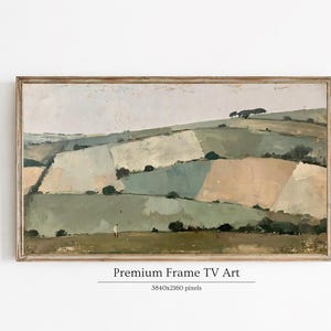 May include: A rectangular landscape painting in a wooden frame depicting rolling hills with patches of muted green, beige, and white fields. A small figure stands in the foreground of the grassy meadow under a pale sky. Text reads Premium Frame TV Art.