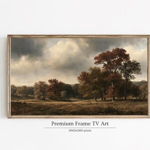 May include: A rectangular landscape painting in a wooden frame depicting a field with trees in autumn colors under a cloudy sky. The text below the frame reads Premium Frame TV Art and 3840x2160 pixels. The scene features brown and orange foliage.