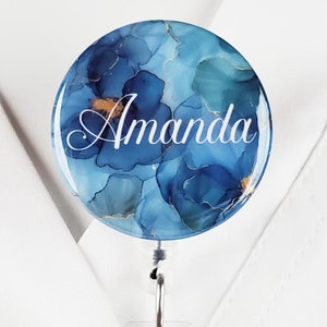 Puede incluir: Un portagafete retr&aacute;ctil azul y dorado con el nombre "Amanda" impreso en la parte delantera.
