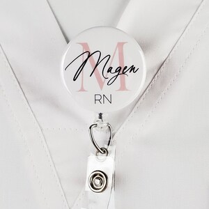 May include: White badge reel with a pink and black personalized badge holder that says "Magen RN".