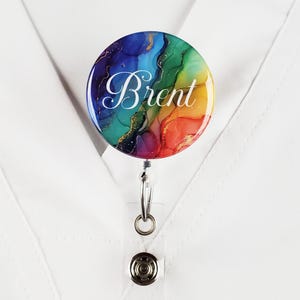 Puede incluir: Un carrete de credencial colorido con un dise&ntilde;o abstracto de arco&iacute;ris y el nombre "Brent" en letras blancas.