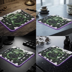 May include: A rectangular mouse pad with a purple edge, featuring a graphic of a green cobra snake coiled around a skull. The text STRIKE FIRST is printed in a bold, stylized font above the snake. The design includes abstract green smoke.