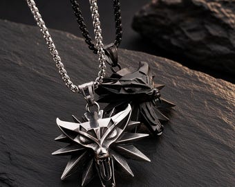 May include: Two metal necklaces featuring stylized wolf head pendants. One pendant is polished silver-tone metal on a matching silver-tone chain, while the other is matte black metal on a matching black chain. Both pendants have sharp, angular features.