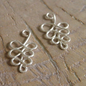 May include: Two silver wire charms shaped like grape clusters. Each charm has a loop at the top for attaching to jewelry.