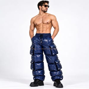Puede incluir: Pantalones cargo acolchados de color azul marino brillante con diseño de cintura alta, cintura elástica, cierre de cordón y cuatro grandes bolsillos rectangulares con solapa en las piernas. Tienen una textura acolchada y acabado brillante.