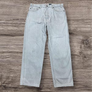May include: Light-wash blue denim jeans featuring a classic five-pocket design, a button fly closure, and a straight-leg cut. The fabric displays a faded, worn-in appearance with visible stitching along the seams and a standard waistband with belt loops.