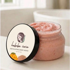 May include: A clear plastic jar filled with pink exfoliating body scrub, accompanied by a black lid featuring the Haboba Care logo, a stylized illustration of a person, a mango graphic, and the text EXFOLIATING BODY SCRUB NET WT 6OZ.