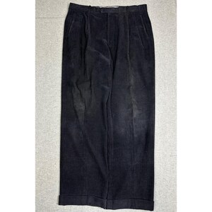 May include: A pair of black corduroy trousers featuring a high-waisted design with a button closure, a zippered fly, and two side pockets. These pants have a straight-leg cut and are finished with a cuffed hem at the bottom of each leg.
