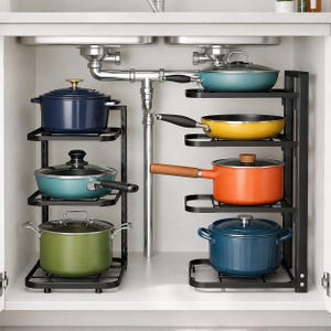 May include: A black metal under-sink storage rack with multiple tiers holding various colourful cookware, including a dark blue pot, a teal pan, a green pot, a teal skillet, a yellow pan, an orange pot, and a blue pot with lids.