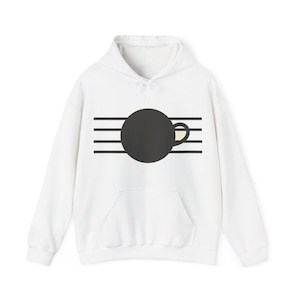 May include: A white hooded sweatshirt featuring a graphic design on the chest. The design consists of a large solid black circle centred over four horizontal black lines, with a small cream-coloured handle shape extending from the right side.