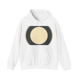 May include: A white hooded sweatshirt featuring a central graphic design. The design consists of a large cream-coloured circle centred within a dark charcoal grey rectangular shape with rounded sides, framed by thin gold-toned lines on the edges.