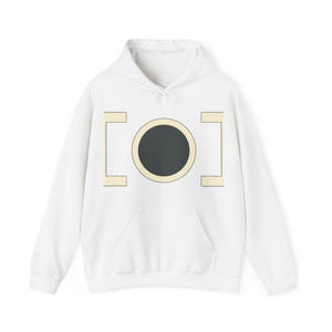 Op de afbeelding: Een witte hoodie met een centraal grafisch ontwerp. Het ontwerp bestaat uit een effen donkergrijze cirkel omsloten door een lichtbeige ring, geflankeerd aan de linker- en rechterkant door twee verticale lichtbeige rechthoekige beugels.