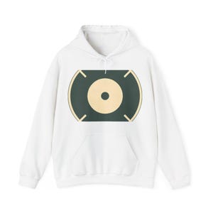 Puede incluir: Una sudadera con capucha blanca que presenta un diseño gráfico central. El gráfico consiste en una forma rectangular de color verde oscuro con lados redondeados, que contiene un gran círculo amarillo pálido con un pequeño centro oscuro, enmarcado por cuatro esquinas.