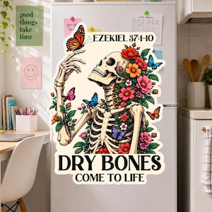 May include: A large decorative magnet featuring a skeleton adorned with colorful flowers and butterflies. The text EZEKIEL 37:1-10 appears at the top, and the words DRY BONES COME TO LIFE are printed in bold black letters at the bottom of the design.