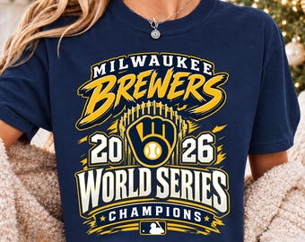 May include: A navy blue t-shirt featuring a yellow and white graphic that reads Milwaukee Brewers 2026 World Series Champions. The design includes a baseball glove logo, the year 2026, and a small Major League Baseball silhouette logo at the bottom.