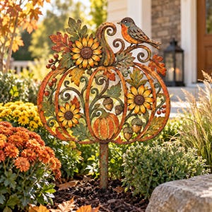 May include: A decorative metal garden stake featuring a large pumpkin silhouette adorned with sunflowers, oak leaves, acorns, and small berries. A small bird with orange and blue plumage is perched on the top scroll of the pumpkin frame.