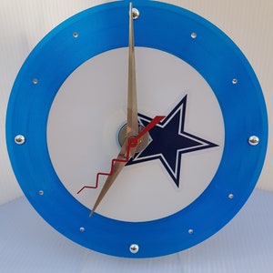 May include: A blue and white clock with a star design. The clock has silver hands and a red second hand.