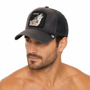 May include: A charcoal gray trucker cap featuring a black rectangular patch on the front with a graphic of a howling wolf and the text LONE WOLF. The hat has a solid front panel, a curved brim, and a breathable mesh back with a small metal logo tag.