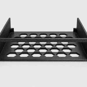 Puede incluir: Un estante de montaje en rack negro que presenta una base plana con un patr&oacute;n de recortes hexagonales repetitivos para ventilaci&oacute;n. La unidad incluye dos paredes laterales y una placa frontal con cuatro orificios de montaje para rack.