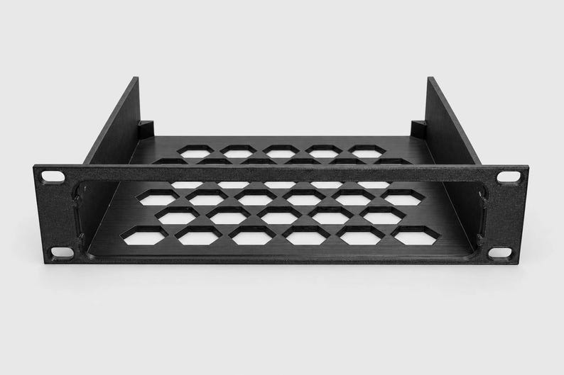 Puede incluir: Un estante de montaje en rack negro que presenta una base plana con un patr&oacute;n de recortes hexagonales repetitivos para ventilaci&oacute;n. La unidad incluye dos paredes laterales y una placa frontal con cuatro orificios de montaje para rack.