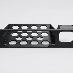 K&ouml;nnte beinhalten: Ein schwarzes Rack-Montage-Regal mit einem sechseckigen Wabenmuster auf der Basis zur Bel&uuml;ftung. Die Frontplatte verf&uuml;gt &uuml;ber vier Befestigungsl&ouml;cher und einen quadratischen Ausschnitt auf der rechten Seite f&uuml;r die Rack-Installation.