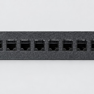 Pode incluir: Um painel de conex&atilde;o de rede em metal preto com dez portas Ethernet RJ45 dispostas em uma &uacute;nica linha horizontal. O painel retangular inclui quatro orif&iacute;cios de montagem, um em cada canto, para instala&ccedil;&atilde;o em rack padr&atilde;o.