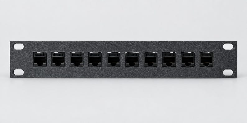 Pode incluir: Um painel de conex&atilde;o de rede em metal preto com dez portas Ethernet RJ45 dispostas em uma &uacute;nica linha horizontal. O painel retangular inclui quatro orif&iacute;cios de montagem, um em cada canto, para instala&ccedil;&atilde;o em rack padr&atilde;o.