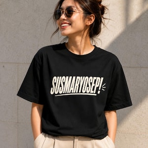 May include: A black short-sleeved t-shirt featuring the text SUSMARYOSEP! printed in a bold, cream-coloured sans-serif font across the chest. The design includes a horizontal line underneath the text and a small graphic element to the right.