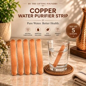 Puede incluir: Un juego de cinco tiras de cobre rectangulares para purificar agua con extremos redondeados. Cuatro tiras están colocadas verticalmente en fila, mientras que una tira está sumergida en un vaso con agua. El texto dice Copper Water Purifier Strip.