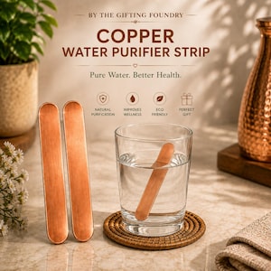 Könnte beinhalten: Zwei rechteckige Wasserreiniger-Streifen aus Kupfer mit abgerundeten Enden stehen aufrecht neben einem klaren Wasserglas, das einen dritten identischen Streifen enthält. Der Text lautet BY THE GIFTING FOUNDRY, COPPER WATER PURIFIER STRIP und Pure Water. Better Health.
