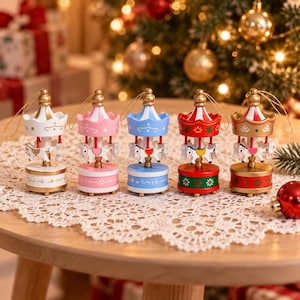 May include: Five small carousel ornaments with gold hanging strings. Each features a central pole with a white horse, a colourful canopy, and a circular base. The colours include white, pink, blue, red with green, and red with gold accents.