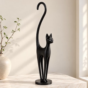 May include: A tall, matte black cat-shaped paper towel holder featuring a slender, stylized feline figure with an elongated, curved tail that acts as the central post. The structure stands on a circular base, designed to hold a roll of paper towels.