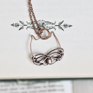 Peut inclure: Un collier en fil de cuivre avec un pendentif en forme de chat. Le pendentif est fait de fil torsadé en forme de visage de chat avec une petite perle pour le nez.